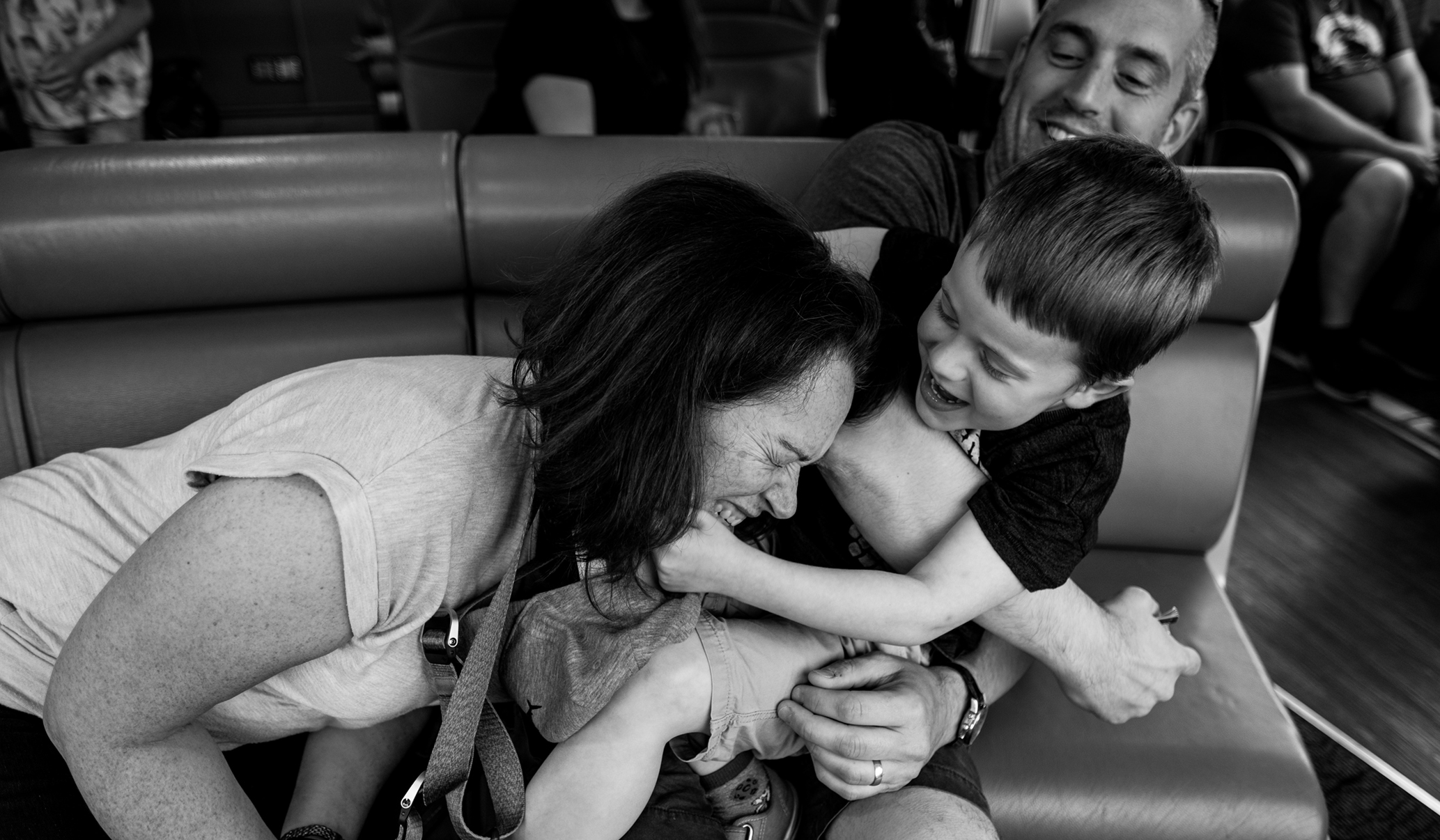 boy pulling mom's head towards him while on aa boat ride on the Thames during a documentary family photoshoot